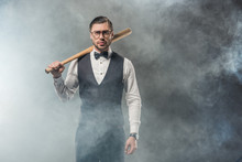 Stylish Man In Bow Tie And Eyeglasses Holding Baseball Bat And Looking At Camera In Smoke