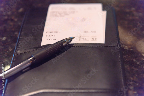 Fotografie, Obraz Open leather check holder with restaurant bill and pen