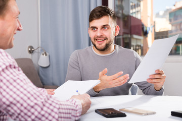 Wall Mural - Happy man discussing papers with male colleague