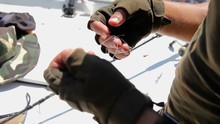 Men's Gloved Hands Untangle Fishing Line. Unravel The Tangle Of Fishing Line On The Background Of The Boat