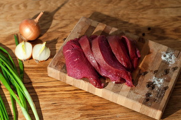 Raw pork steaks on wooden board with and salt, pepper. Meat for grill or BBQ on cutting board over aged wooden background, top view. Process of cooking healthy meal.