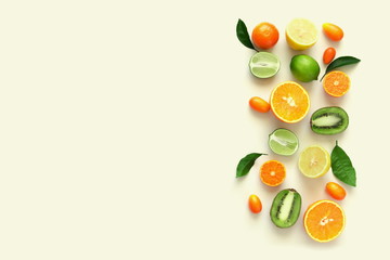 Wall Mural - Fruit background. Summer concept. Colorful fresh citrus fruit on a light pastel yellow background table. Orange, tangerine, lime, kiwi. Flat lay, top view, copy space 