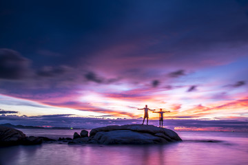 Exposure boy stay on the rock stone on Pattaya beach at sunset time with blue cloud and sunset time background.