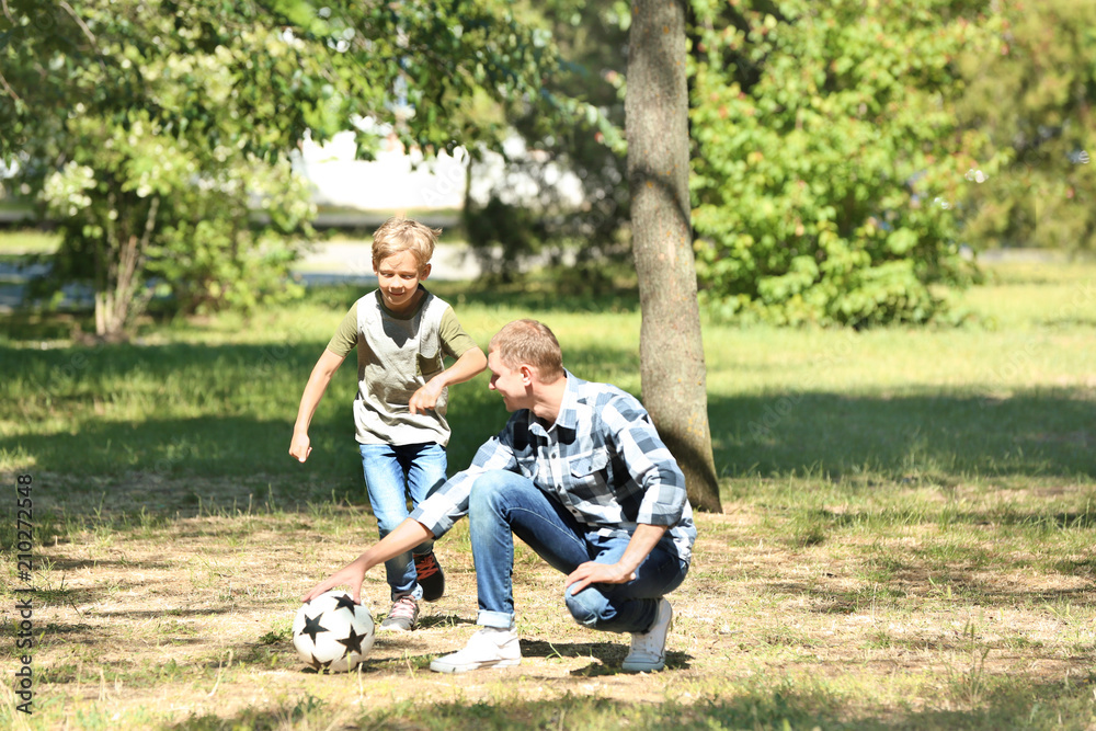 Happy father and son playing football in park