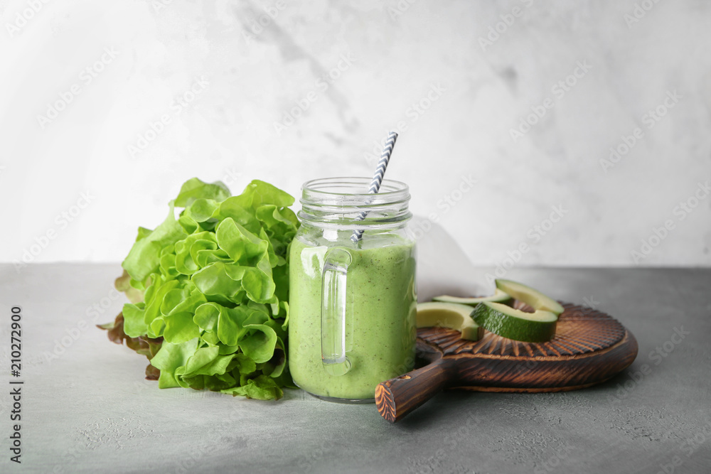Mason jar with tasty smoothie and ingredients on table