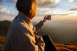 woman traveler drinks coffee with a view of the mountain landscape. A young tourist woman drinks a hot drink from a cup and enjoys the scenery in the mountains. Trekking concept