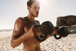 © Jacob Lund - Man doing fitness training at the beach using kettlebells