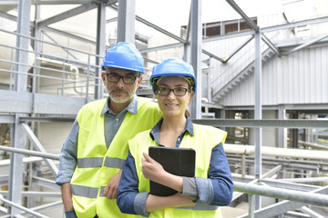 Wall Mural - Portrait of smiling industrial engineers standing in recycling plant