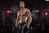 Fototapeta Tęcza - Young handsome sportsman bodybuilder weightlifter with an ideal body, after coaching poses in front of the camera, abdominal muscles, biceps triceps. In sportswear.