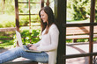 © ViDi Studio - Young successful businesswoman in light casual clothes. Smiling Woman working on modern laptop pc computer in city park in street outdoors on spring nature. Mobile Office. Freelance business concept.