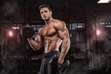 Young handsome sportsman bodybuilder weightlifter with an ideal body, after coaching poses in front of the camera, abdominal muscles, biceps triceps. In sportswear.