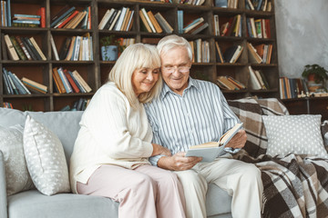 Wall Mural - Senior couple together at home retirement concept reading book hugging