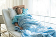 Asian depressed elderly woman patients lying on bed looking out the window in hospital. Elderly woman patients is glad recovered from the illness.