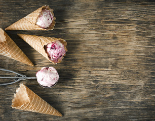 Canvas Print - Raspberry vanilla ice cream scoop in a spoon with waffles cones on wooden background