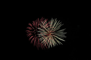 Two fireworks exploding at once with red and yellow.