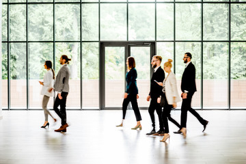 Wall Mural - Business people walking at the modern hall on the window background indoors. long exposure image technic with motion blurred people