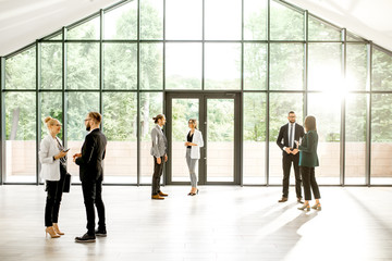 Business people at the spacious modern hall with big window overlooking on the park. Wide view with copy space