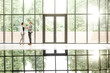 © rh2010 - Business couple standing together at the modern office hall with window on the background overlooking on the park. View directly with reflection from the table