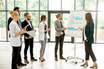 Wall Mural - A group of business people standing together during the conference with flip chart at the modern office