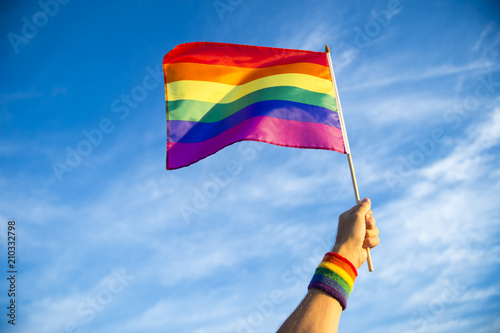 Fotografía Colorful rainbow gay pride flag being waved in the breeze by a hand wearing a s