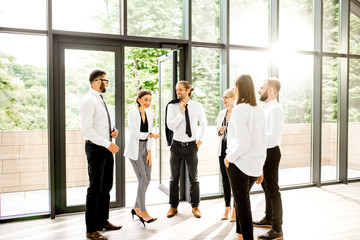 Business people strictly dressed in white having a conversation standing together at the office hall