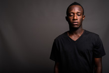 Young African Man Wearing Black Shirt Against Gray Background