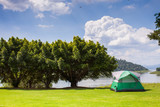 Fototapeta  - Camping tent on green grass field under clear sky 