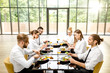 © rh2010 - Business people dressed in white shirts sitting together during a business lunch with delicious meals and wine in the modern restaurant