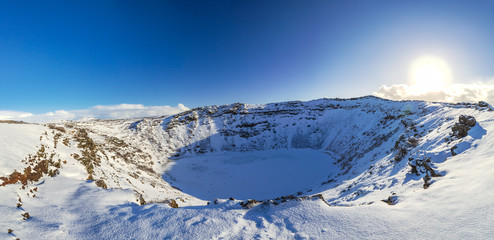 Panoramic view of the Kerid Volcano  Iceland with snow and ice in the volcanic crater lake in Winter under a blue sky