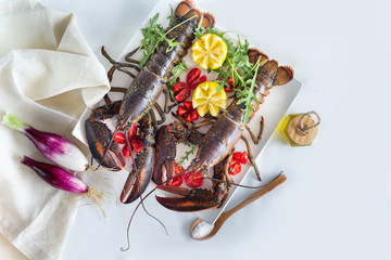 TWO RAW ORGANIC LOBSTERS WITH LEMON AND TOMATOES. INGREDIENTS FOR CATALAN LOBSTER.SELECTIVE FOCUS.TOP VIEW