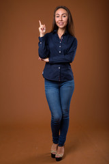 Studio shot of young beautiful businesswoman against brown backg