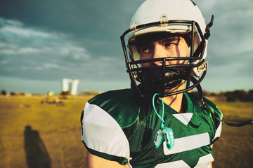 Wall Mural - Young American football player standing alone on a field