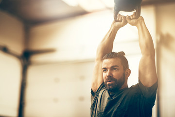 Wall Mural - Fit young man swinging a dumbbell at the gym