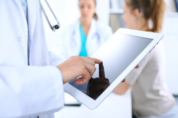 Doctor using tablet computer, close-up of hands at touch pad screen