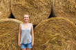 © AnastazjaSoroka - A smiling young woman with blond hair stands on the background of haymaking.