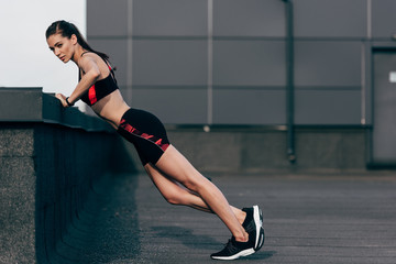 Wall Mural - young focused sportswoman doing push up on roof