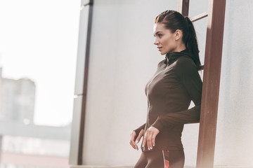 Wall Mural - sportswoman posing in thermal clothes near ladder on roof