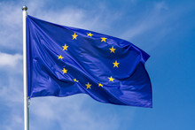 Flag Of The European Union Waving In The Wind On Flagpole Against The Sky With Clouds On Sunny Day, Close-up