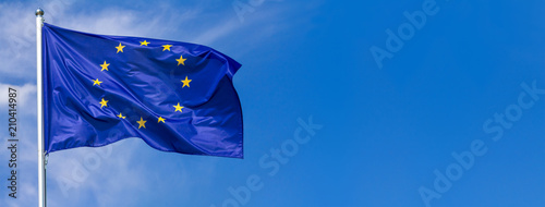 Fotomural Flag of the European Union waving in the wind on flagpole against the sky with c