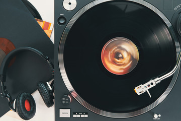 Turntable vinyl record player and black headphones on the background white wooden boards. Sound technology for DJ to mix & play music. Blue vinyl records. Different in size vinyl records             