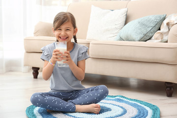 Sticker - Cute little girl drinking milk on floor at home