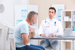 © New Africa - Coughing mature man visiting doctor at clinic