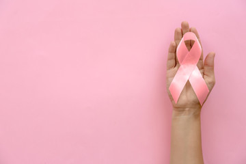 Poster - Woman holding symbolic ribbon of breast cancer awareness on color background, top view. Gynecological care