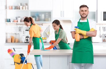 Canvas Print - Team of professional janitors in uniform cleaning kitchen