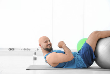 Sticker - Overweight man doing exercise with fitness ball in gym