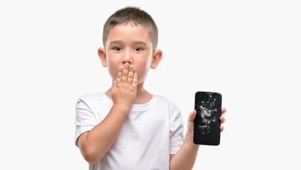 Canvas Print - Dark haired little child holding broken smartphone cover mouth with hand shocked with shame for mistake, expression of fear, scared in silence, secret concept