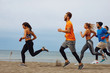© djile - Group of young sports people running on the beach by the sea