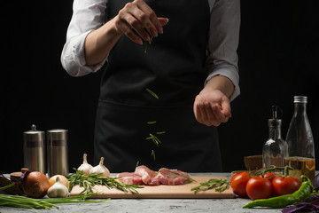 Steak for grilling for chefs. Preparation of fresh beef or pork. Sprinkle with rosemary. Horizontal photo with dark black background.