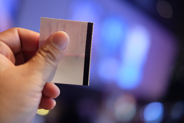 Young man's hand holding a paper ticket