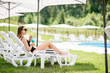 © rh2010 - Young woman in black swimsuit relaxing with cocktail lying on the sunbed at the swimming pool outdoors